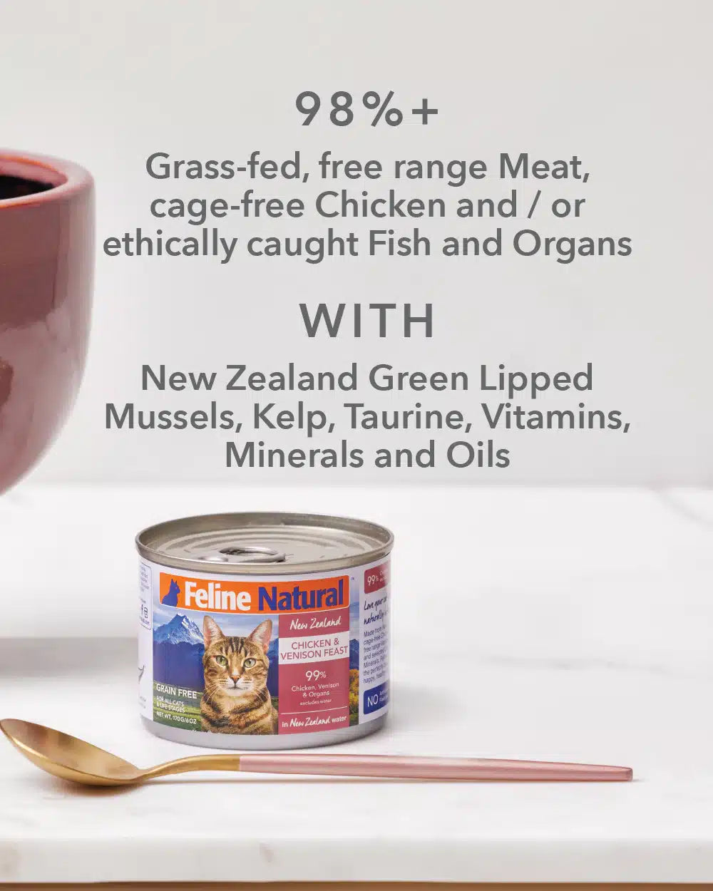 Feline Natural Canned Food for Cats: A can of New Zealand Chicken & Venison Feast, highlighting 99% Chicken, Venison & Organs, grain-free, with a gold-and-blushāpink spoon beside it.