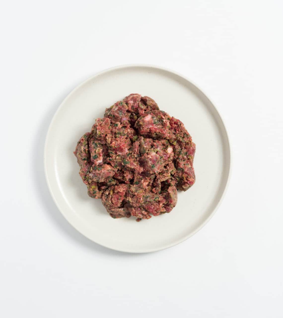 Rawbone Mixed Protein Kangaroo Meal on a white plate, showcasing seasoned raw ground meat mixed with herbs, ideal for species-appropriate pet nutrition.