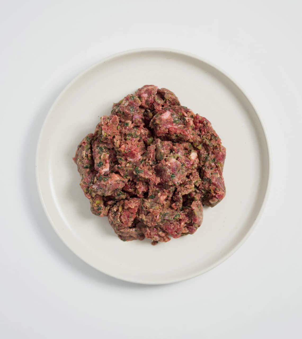 Rawbone Mixed Protein Beef Meal on a white plate, showcasing raw minced beef mixed with herbs and seasonings, emphasizing a ready-to-serve, nutritious pet meal.