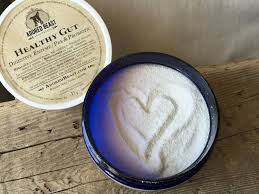 Adored Beast Healthy Gut jar with lid, featuring a heart drawn in the powder, indicating its use as an exfoliating skincare treatment.