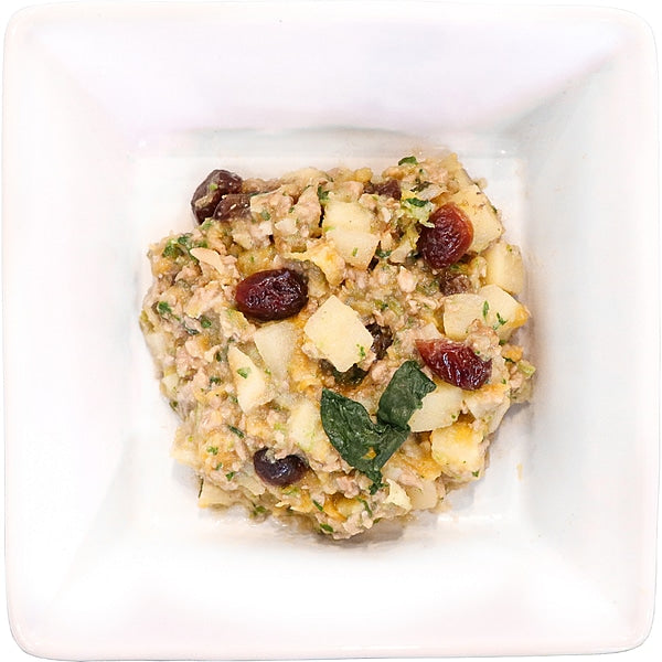Tom & Sawyer Turkey Gobbler: A chunky mix of turkey, apples, dried cranberries, herbs, and breadcrumbs in a white dish, ideal for dog meals or toppers.