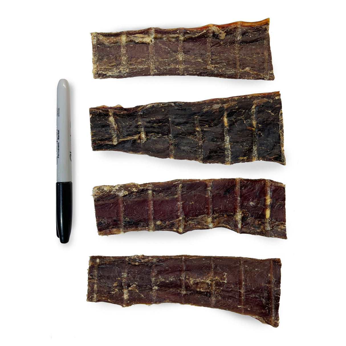 Four One Ingredient 6 Beef Jerky Strips, dark and flat, next to a Sharpie for scale, showcasing their size and easy-to-chew texture for dogs.