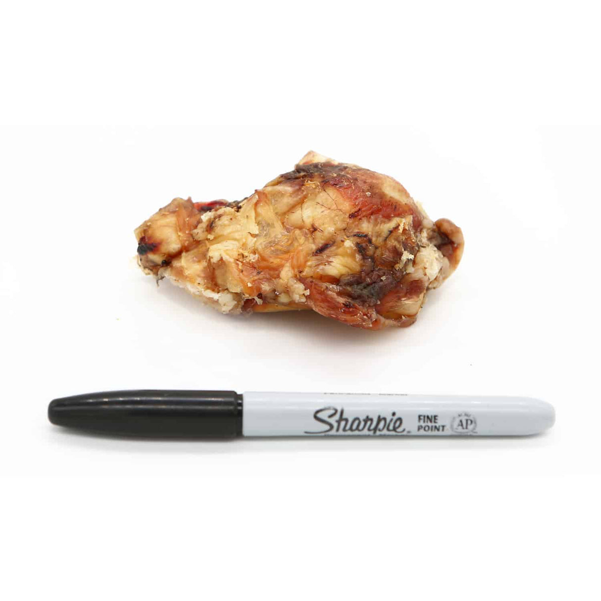 One Ingredient Dehydrated Beef Kneecap next to a Sharpie marker, showcasing its size. A durable, natural chew for medium to large dogs.