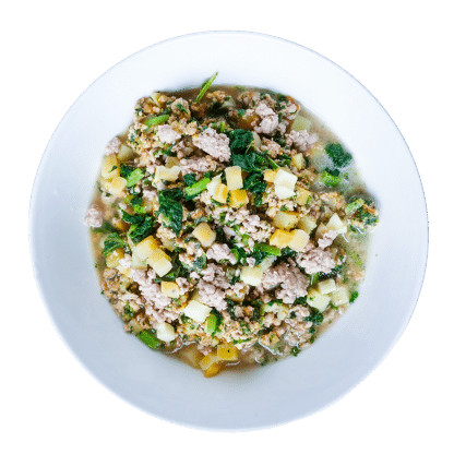 Tom & Sawyer Classic Pork Stew features crumbled pork, diced potatoes, leafy greens, and herbs in a light broth, offering a hearty, gently cooked meal option.