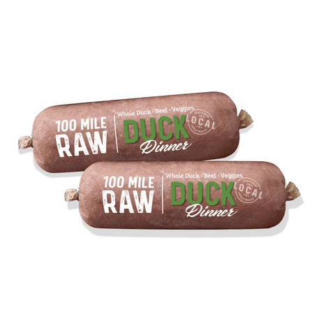 100 Mile Raw Duck Dinner: Two cylindrical raw food rolls labeled for dogs, featuring whole duck, beef organs, and veggies, locally sourced within 100 miles of Vancouver.