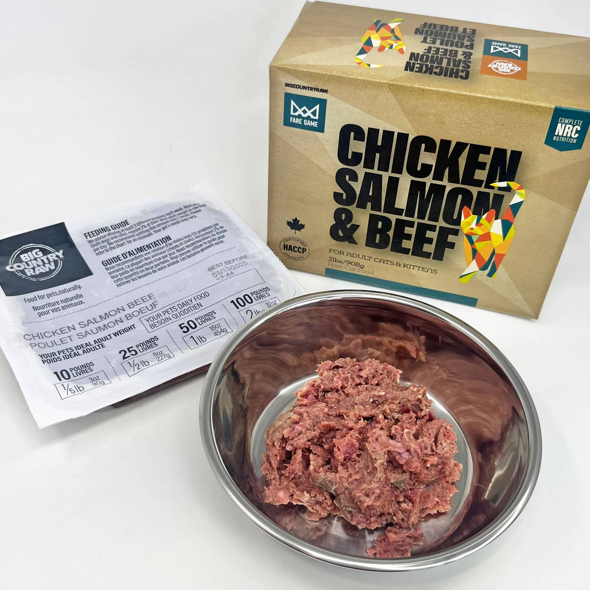 Fare Game Chicken & Salmon with Beef by Big Country Raw: Stainless-steel bowl with pink raw meat blend; packages labeled for adult cats and kittens' complete raw diet.