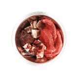 Stainless-steel bowl with True Carnivores branding, showcasing 100 Mile Raw Just Beef mix of red meat cuts, organ pieces, and bone fragments for pets.
