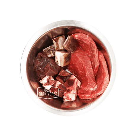 Stainless-steel bowl with True Carnivores branding, showcasing 100 Mile Raw Just Beef mix of red meat cuts, organ pieces, and bone fragments for pets.
