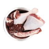 Stainless-steel bowl with turkey drumsticks, neck, and giblets, featuring the True Carnivores logo; 100 Mile Raw Just Turkey, a locally sourced, single-protein pet food.