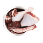 Stainless-steel bowl with turkey drumsticks, neck, and giblets, featuring the True Carnivores logo; 100 Mile Raw Just Turkey, a locally sourced, single-protein pet food.