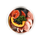 Stainless-steel bowl labeled “True Carnivores” with salmon steaks, red meat, pumpkin, blueberries, and kale, showcasing 100 Mile Raw Pork Dinner's locally sourced ingredients.