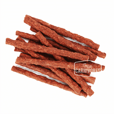 One Ingredient Beef Sticks 150g, featuring a small pile of thin jerky sticks with the True Carnivores logo, ideal for dog chews and training treats.