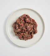 Rawbone Mixed Protein Beef Meal on a white plate, showcasing raw minced beef mixed with herbs and seasonings, emphasizing a ready-to-serve, nutritious pet meal.