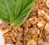 Tom & Sawyer Italian Beef Pasta close-up: stir-fried minced beef, pasta, and seafood in chili paste, garnished with fresh basil.