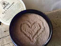 Adored Beast Gut Soothe tub with exposed beige powder, heart-shaped imprint, and lid aside; digestive support with prebiotics and probiotics.