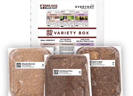 RDBK Everyday Raw Variety Box showing a printed insert and three vacuum-sealed 1 lb raw-food pucks: Classic Harvest, Farmhouse Fare, Reef n’ Beef.