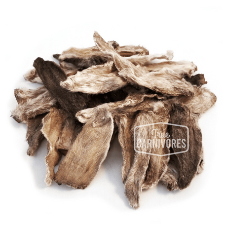 One Ingredient Rabbit Ears 55g shows a pile of dried rabbit ears with fur, marketed as a natural chew treat for cats and dogs, promoting digestive health.