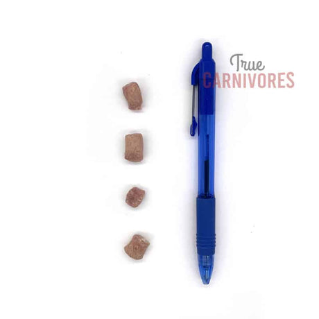 One Ingredient Freeze-Dried Rabbit Bites 60g, four cube-shaped pieces beside a pen for scale; low-allergen, high-protein pet treats from True Carnivores.