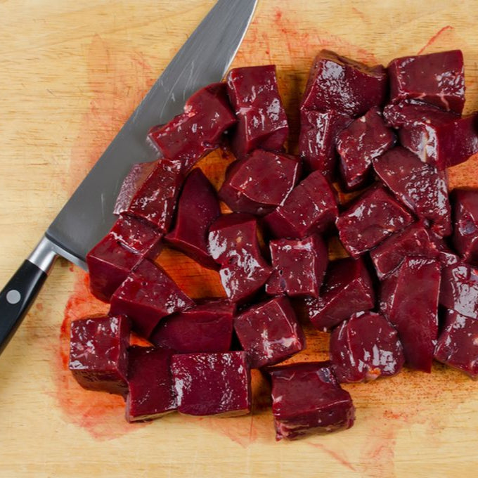 Diced raw beef on a wooden cutting board with a knife