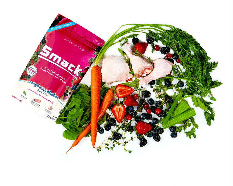 Smack Very Berry Chicken for Dogs pouch surrounded by raw chicken, carrots, celery, spinach, mixed berries, and herbs, highlighting its dehydrated raw superfood blend.